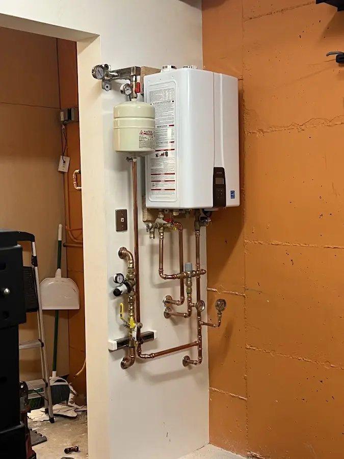 Plumbing technician inspecting water heater connections in West Peoria